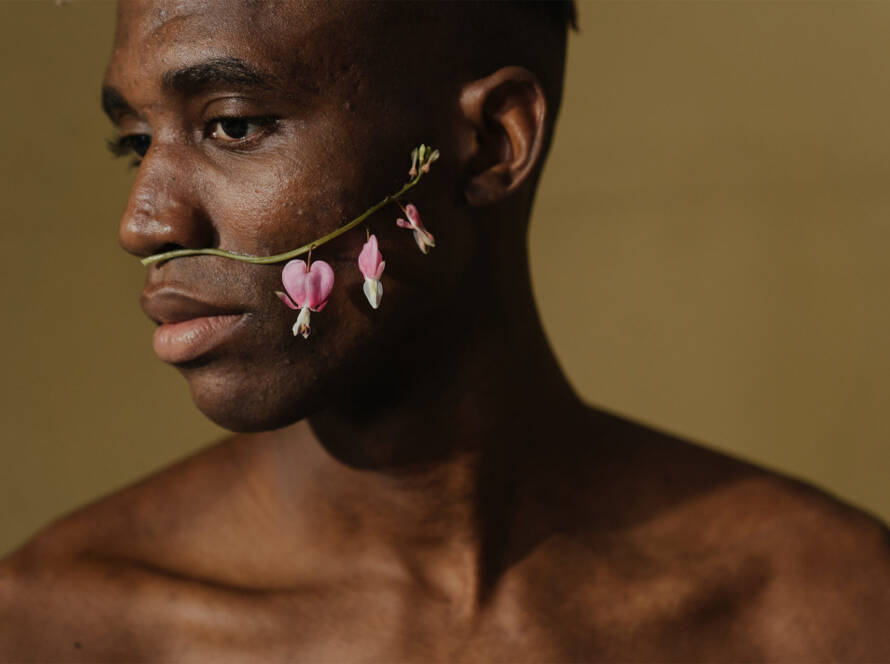 homme noir avec des fleurs sur le visage sur un fond neutre avec de